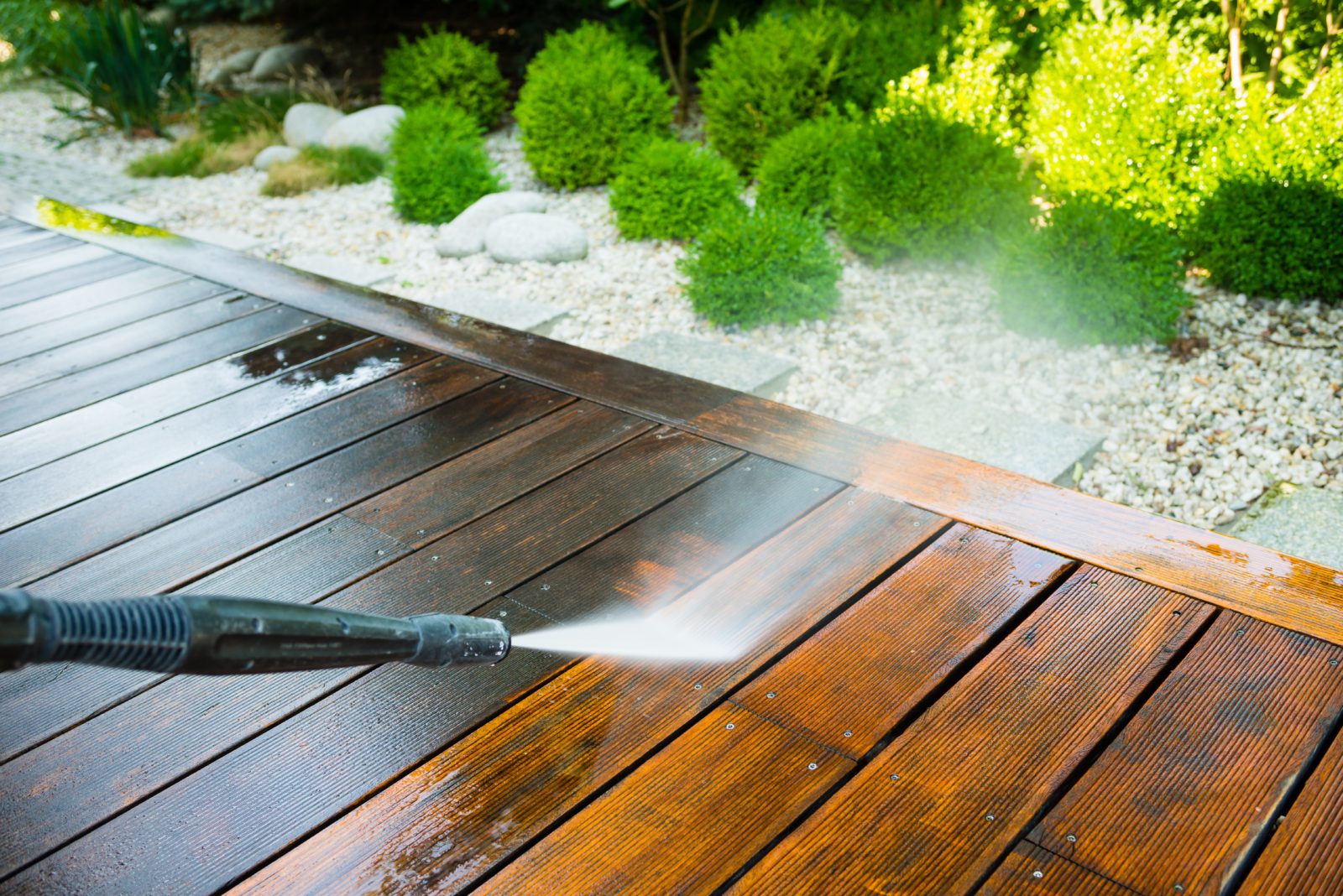 cleaning terrace with a power washer - high water pressure cleaner on wooden terrace surface